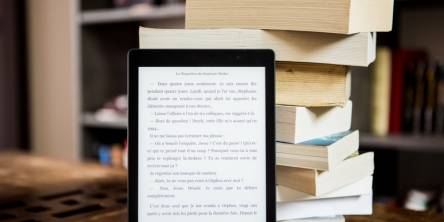 ebook reader in front of a pile of books