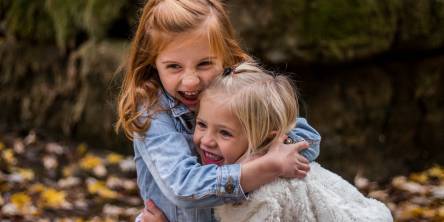 Two little girls outside hugging.